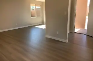 Finished laminate flooring with installed baseboards in a sunlit residential home in Phoenix, AZ.