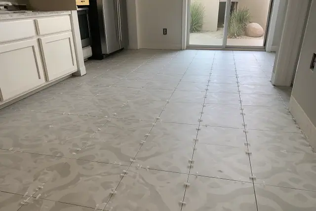 Large-format patterned tile installation with spacers on a kitchen floor in Phoenix, AZ.