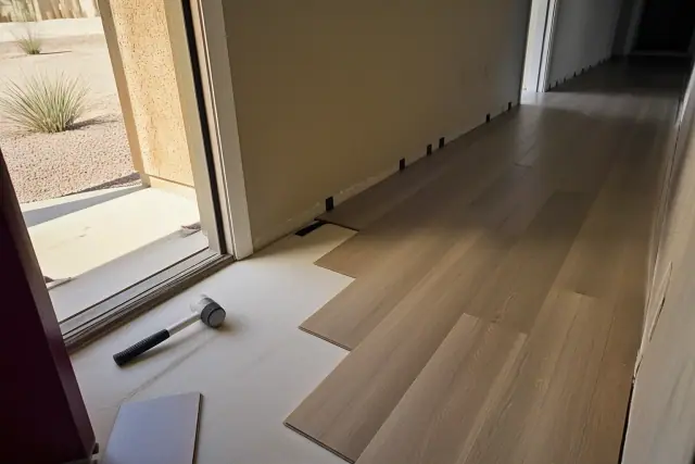 Luxury vinyl plank flooring installation with staggered pattern and tools in a residential hallway in Goodyear, AZ.
