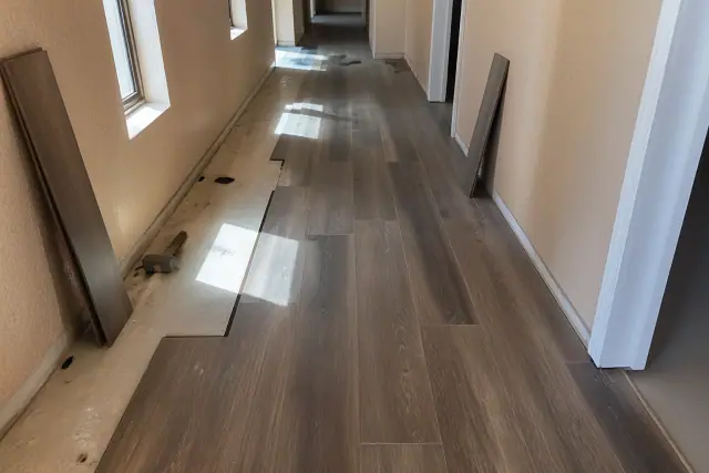 Luxury vinyl plank installation in a hallway in Phoenix, AZ, showing planks being placed in a staggered pattern.
