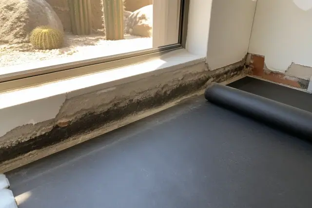 Moisture damage on a concrete slab edge with a protective underlayment membrane in a Phoenix, AZ bathroom.