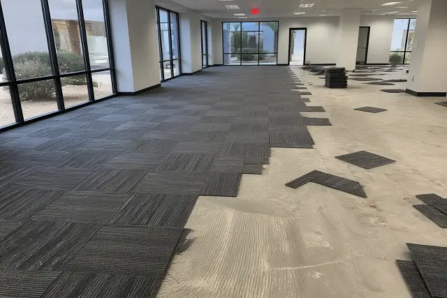 Installation of new carpet tiles in an open office workspace during a renovation in Phoenix, AZ.