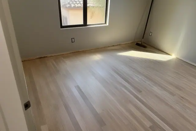 Hardwood flooring planks with sawdust residue from the sanding process in a bedroom in Phoenix, AZ.