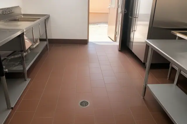Commercial kitchen floor with sealed quarry tile, floor drain, and stainless steel equipment in Phoenix, AZ.