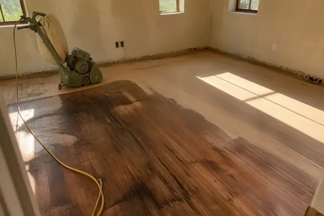 Moisture-damaged hardwood floor planks being restored in a bedroom in Phoenix, AZ.