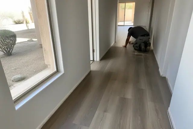 Contractor installing luxury vinyl planks in a staggered pattern in a Phoenix, AZ hallway with desert views.
