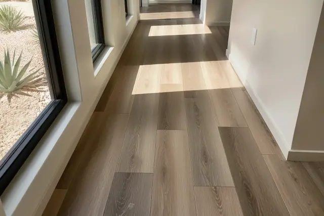 Staggered SPC rigid-core vinyl plank flooring in a Phoenix, AZ residence with sunlight streaming through a window.