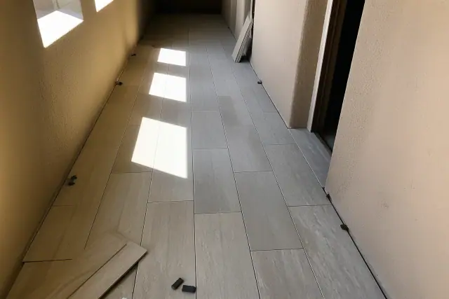 Stone-look vinyl plank flooring installation in progress in a Phoenix, AZ hallway with natural desert sunlight.