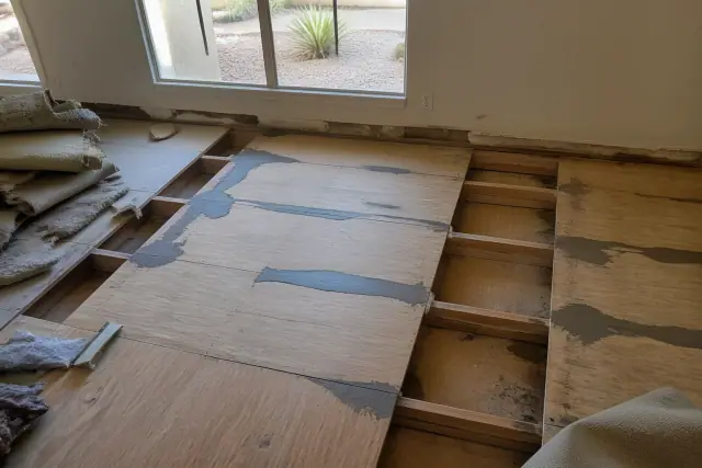 Technician leveling a wooden subfloor and joists during a home floor repair project in Phoenix, AZ.