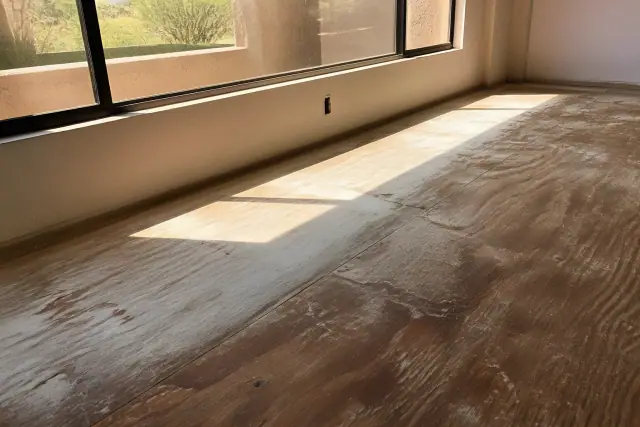 Sun-faded wooden subfloor near a west-facing window in a Phoenix, AZ home.
