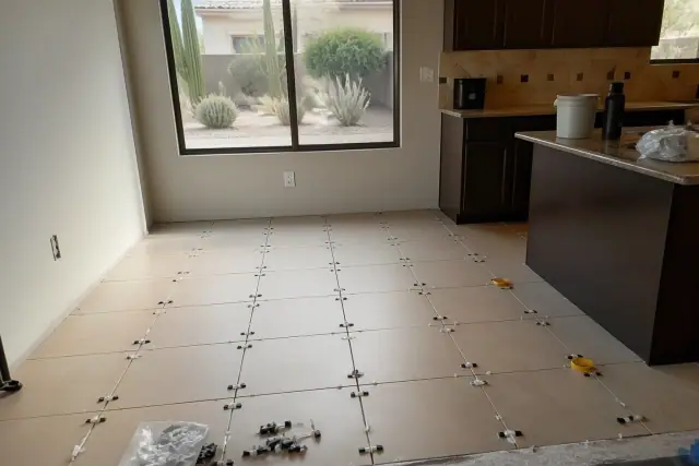Ceramic tile flooring installation with alignment spacers on a kitchen floor in a home in Scottsdale, AZ.