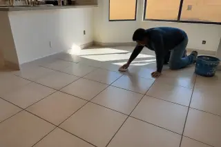 Technician wiping clean the new ceramic kitchen floor in a home in Phoenix, AZ.