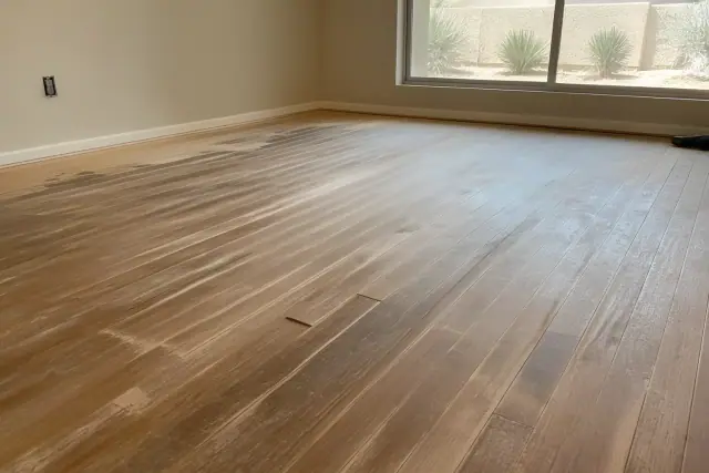 Hardwood floor with water damage and cupping undergoing restoration in a bedroom in Phoenix, AZ.