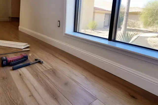 Waterproof rigid-core laminate flooring installation with baseboard trim in a Phoenix, AZ home.
