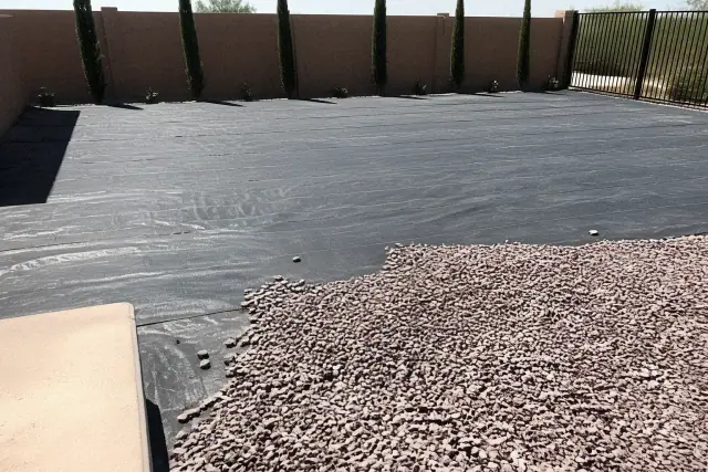 Decorative granite gravel being installed over landscape fabric in a desert yard in Phoenix, AZ.