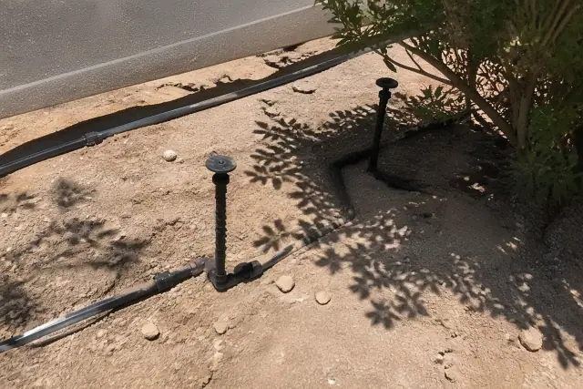Drip and micro irrigation system pipes and sprinkler heads in desert soil under the midday sun in Phoenix, AZ.