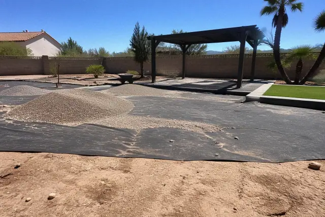 Gravel patio installation on weed barrier fabric with a pergola and turf pad in a backyard in Phoenix, AZ.