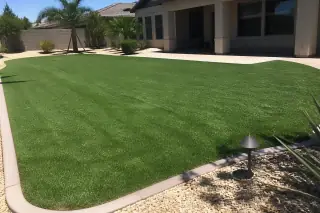 Newly manicured green turf installed in a residential yard under the bright midday sun in Phoenix, AZ.