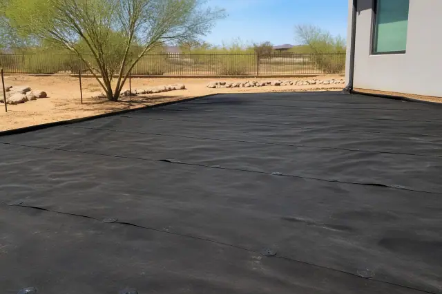 Decomposed granite and river rock landscaping installed over landscape fabric in a Tempe, AZ yard with palo verde trees.