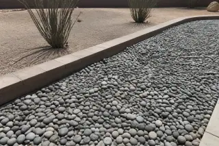 River rock and desert gravel spread along a stone border in a Phoenix, AZ landscape.