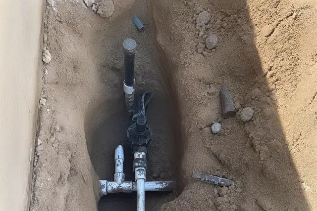 Exposed pipes and sprinkler heads in an excavation for an irrigation system repair in Phoenix, AZ.