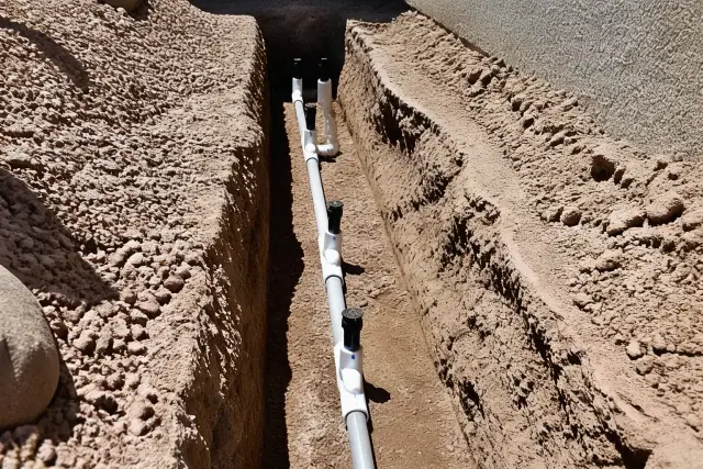 Subsurface irrigation trench showing installed PVC pipes and water-saving nozzles in Phoenix, AZ.