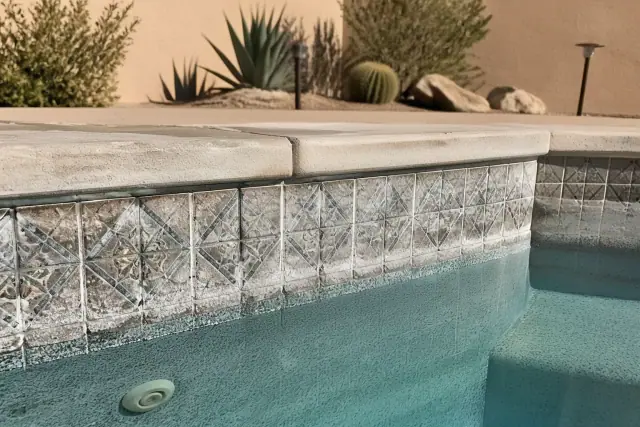 Calcium scale buildup on decorative pool tiles and steps in a Phoenix, AZ backyard.