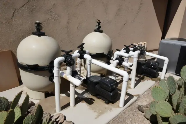 Pool equipment, including tanks and pumps, at a home in Phoenix, AZ, with desert landscaping in the background.
