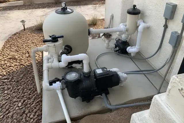 Dual-speed pool pump installed on a concrete slab with plumbing and desert landscaping in Phoenix, AZ.