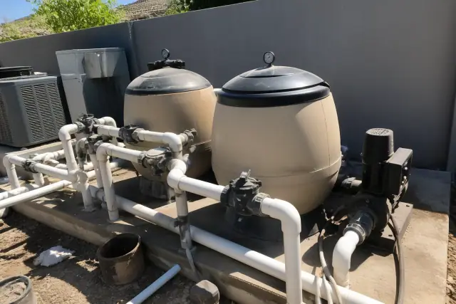 Pool filtration tanks, booster pumps, and plumbing lines at a worksite in Phoenix, AZ.