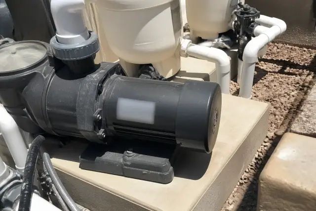 Close-up of a pool pump motor and filtration equipment on a concrete pad at a jobsite in Phoenix, AZ.