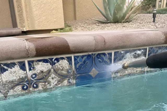 Bead blasting equipment cleaning calcium buildup from ceramic pool tiles in Phoenix, AZ.