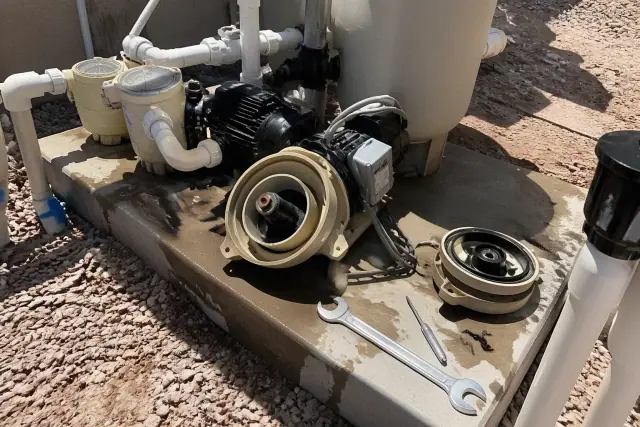 Pool pump impeller repair with tools and exposed plumbing on a concrete equipment pad in Phoenix, AZ.