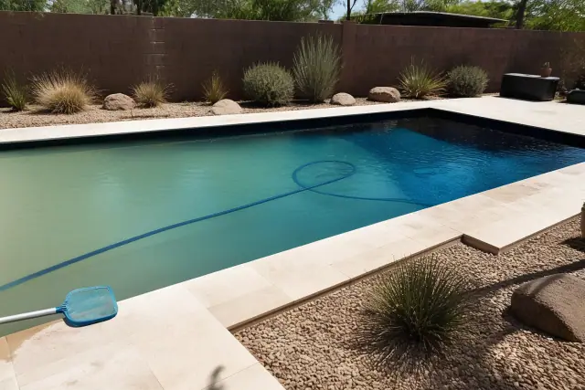 Clear water and cleaning equipment by a rectangular pool in a Phoenix, AZ backyard.