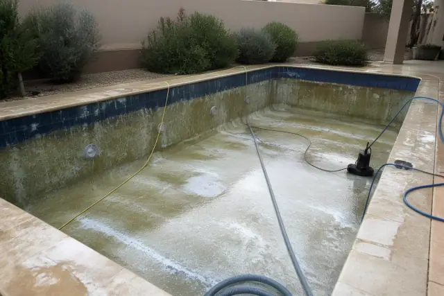 A drained residential pool in Glendale, AZ undergoing an acid wash cleaning process with equipment hoses on the deck.