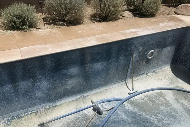 Pool acid wash in progress with tools and hoses on the floor of a swimming pool in Chandler, AZ.