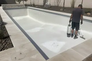 Empty pool with freshly acid-washed plaster floor and cleaning tools in a Phoenix, AZ backyard.