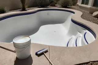 Freshly acid-washed pool surface with a deck brush and bucket on the coping in a Phoenix, AZ backyard.