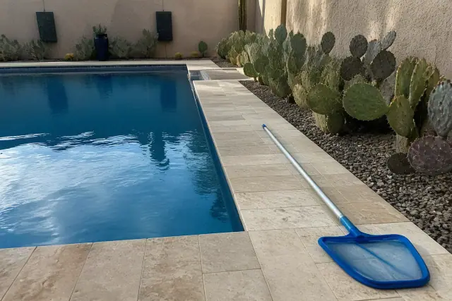 Pool cleaning tools resting on a deck by a residential swimming pool in Peoria, AZ.