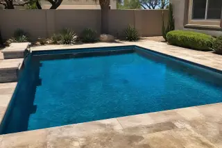 Blue water in a residential rectangular pool with desert landscaping and stone coping in Phoenix, AZ.