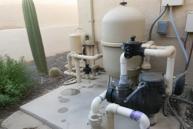 Pool equipment repair on a concrete pad with pump, plumbing, and desert landscaping in Peoria, AZ.