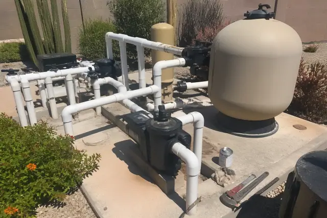 Pool equipment being repaired on a concrete slab in Scottsdale, AZ, with filtration tanks and exposed plumbing.
