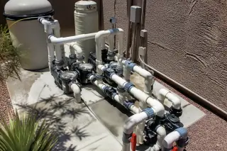 New PVC piping and pool filtration equipment on a concrete slab in a Phoenix, AZ backyard.