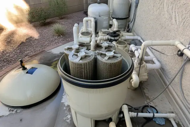 Open pool filter housing with debris-filled cartridges during cleaning in Gilbert, AZ.