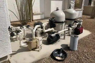 Cleaned pool filtration tanks and organized plumbing on a concrete slab in a Phoenix, AZ backyard.