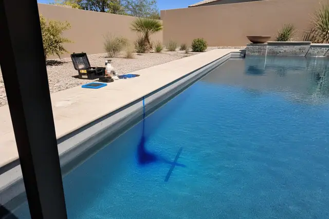 A technician marks a pool leak with dye and tape at a residential backyard pool in Phoenix, AZ.