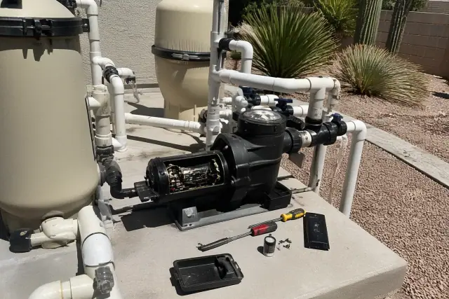 Pool pump motor repair on a concrete slab in Phoenix, AZ, showing internal wiring and filtration equipment.