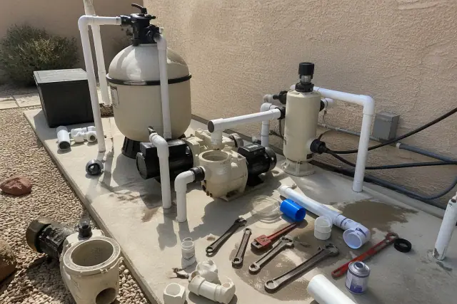 Pool pump repair in progress with tools and plumbing on a concrete slab at a home in Chandler, AZ.