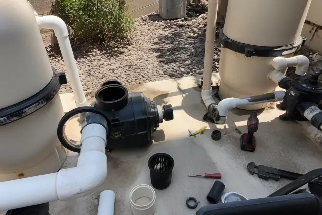 Pool pump repair in progress with tools and open housing on a concrete pool equipment pad in Gilbert, AZ.