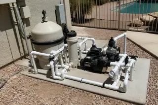 New PVC plumbing and pool pump equipment on a concrete slab in a Phoenix, AZ backyard.